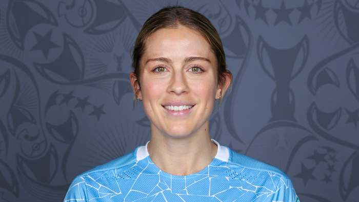 Abby Dahlkemper wears a blue soccer jersey and smiles for the camera.